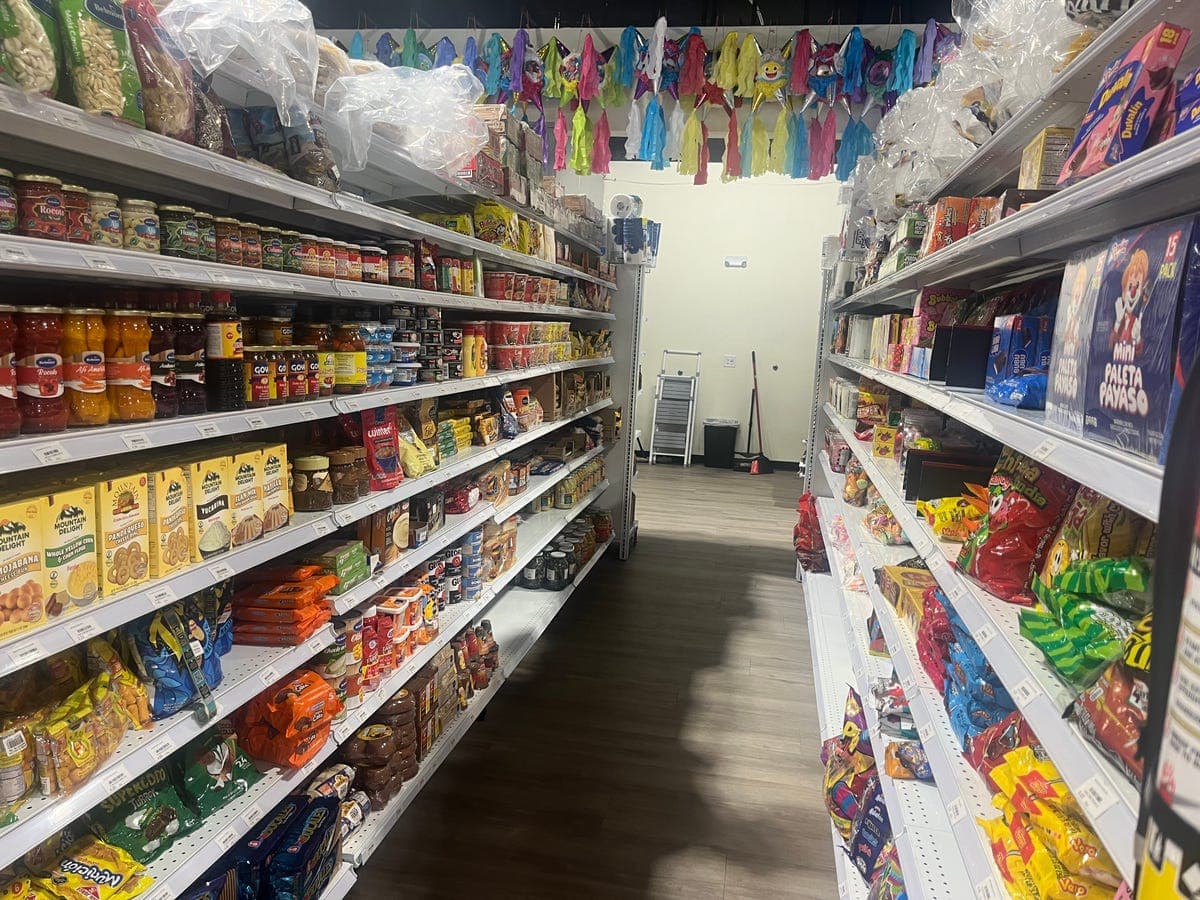 Grocery aisle with colorful piñatas hanging from ceiling at Los Portales